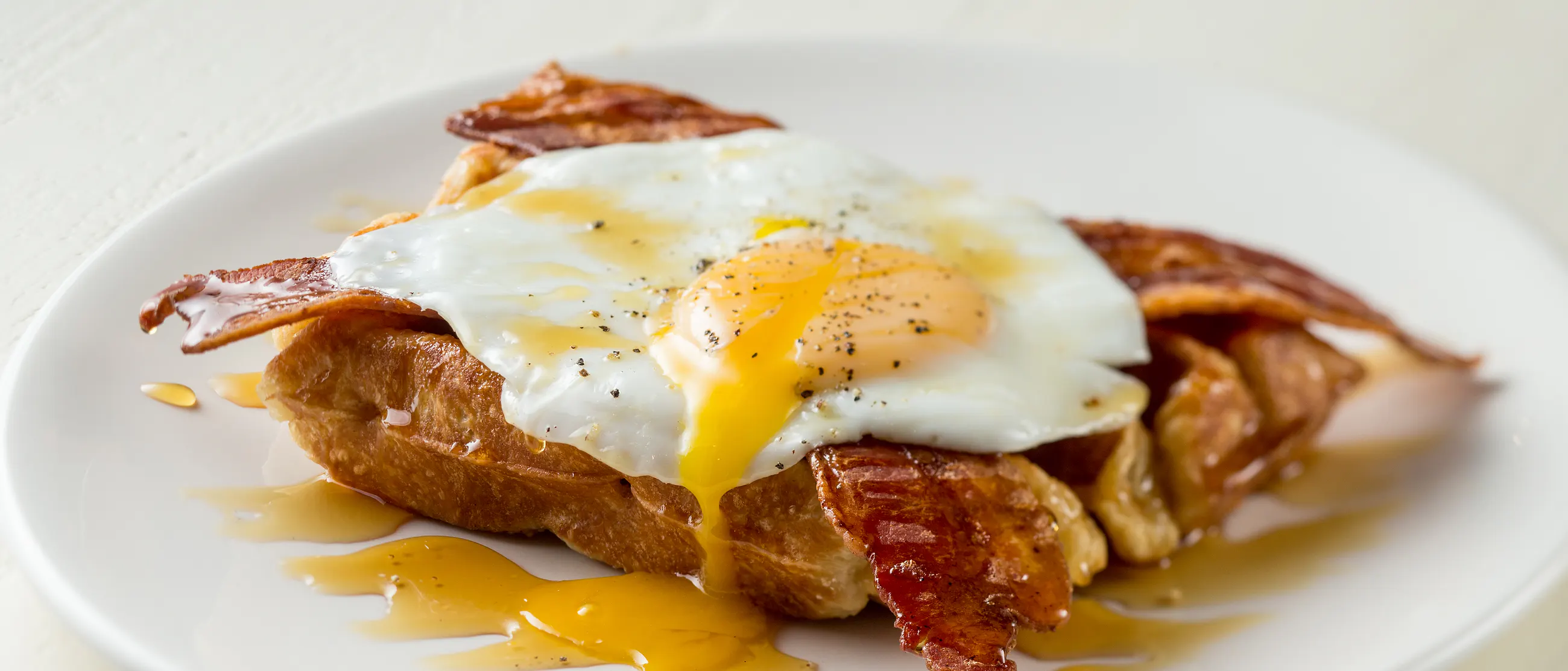Savory breakfast waffle with sunny side up egg, bacon and maple syrup at Off The Waffle, Eugene