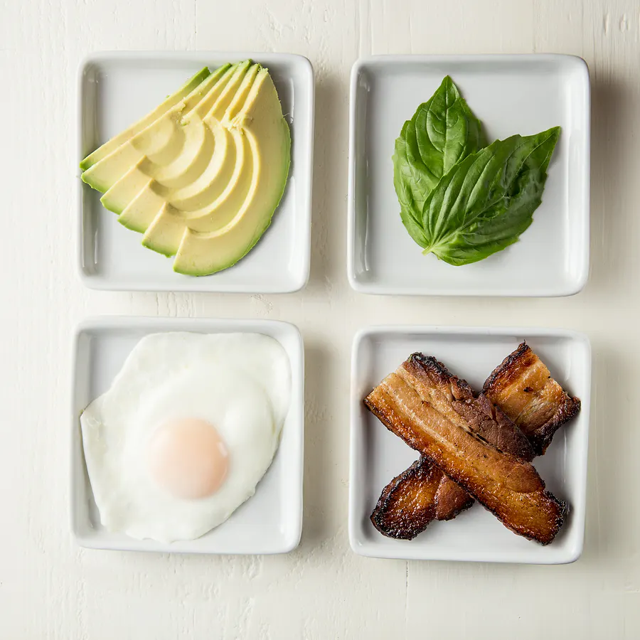 Organic avocado, basil, egg and bacon in prep dishes