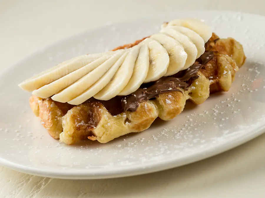 Liège waffle spread with Nutella and fanned organic banana slices, dusted with powdered sugar